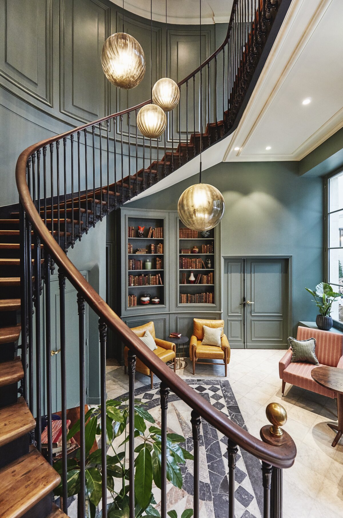 Parisian stairwell with marble floor, staircase with wooden treads, and  metal handrail, teal painted walls with built in shelving