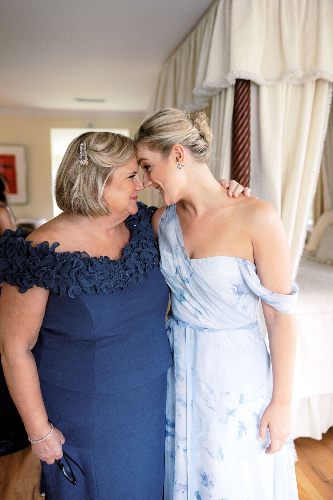 Two ladies dressed in navy and powder blue for a wedding, stand with heads touching, at Lion Rock Farm, CT.  Image by Jenny Fu Studio