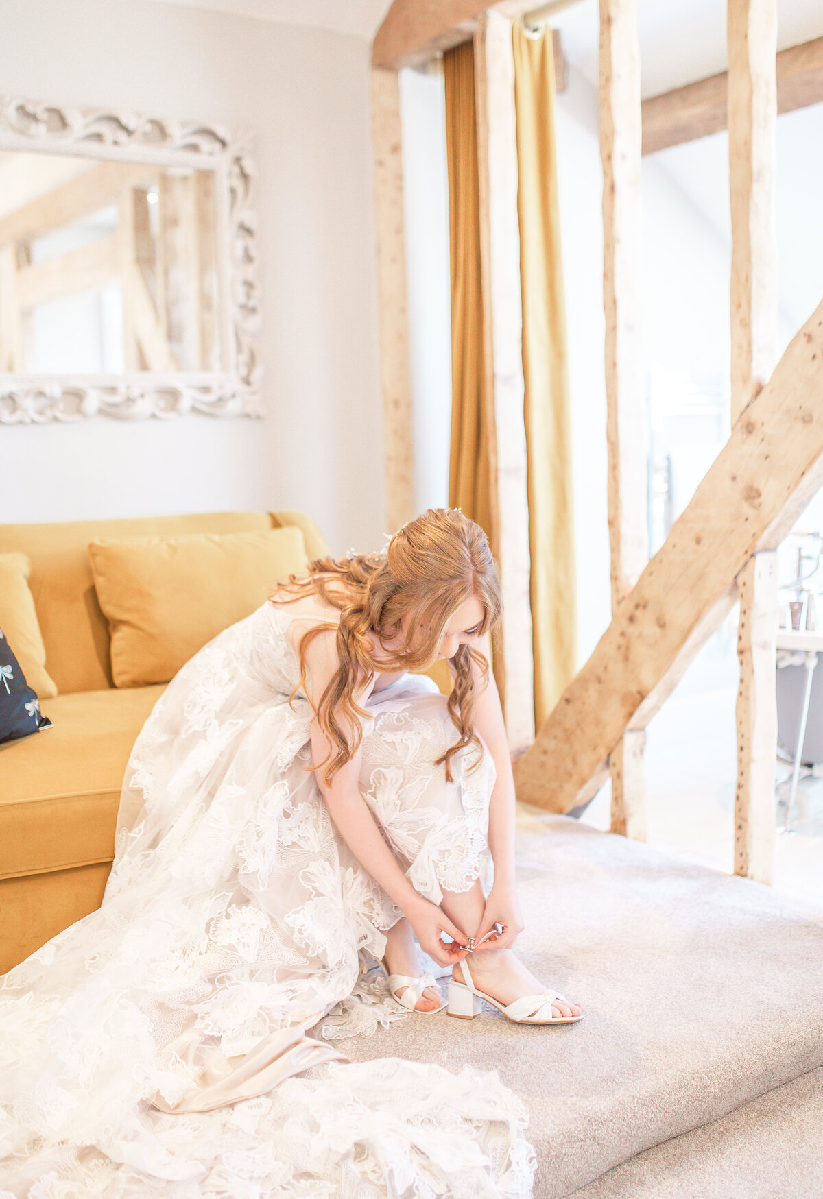 Bride sat down in wedding dress putting on shoes