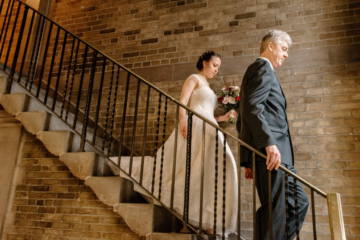 bride and her father walk down staircase