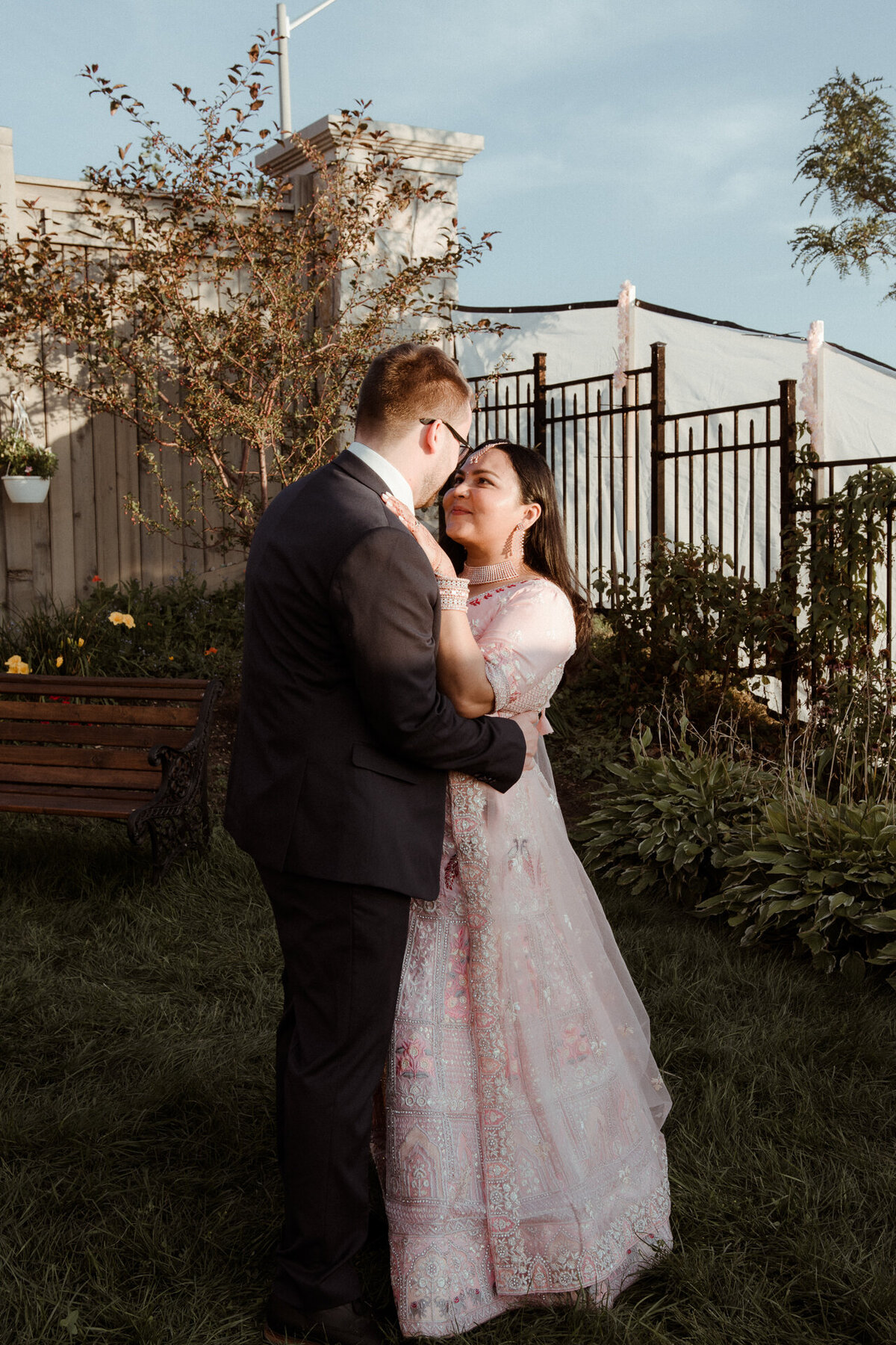 A couple in formal attire sharing an intimate moment in a garden setting.