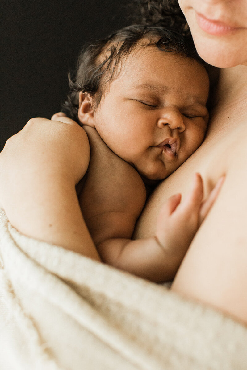 newborn baby is wrapped close to mom’s chest for skin to skin time