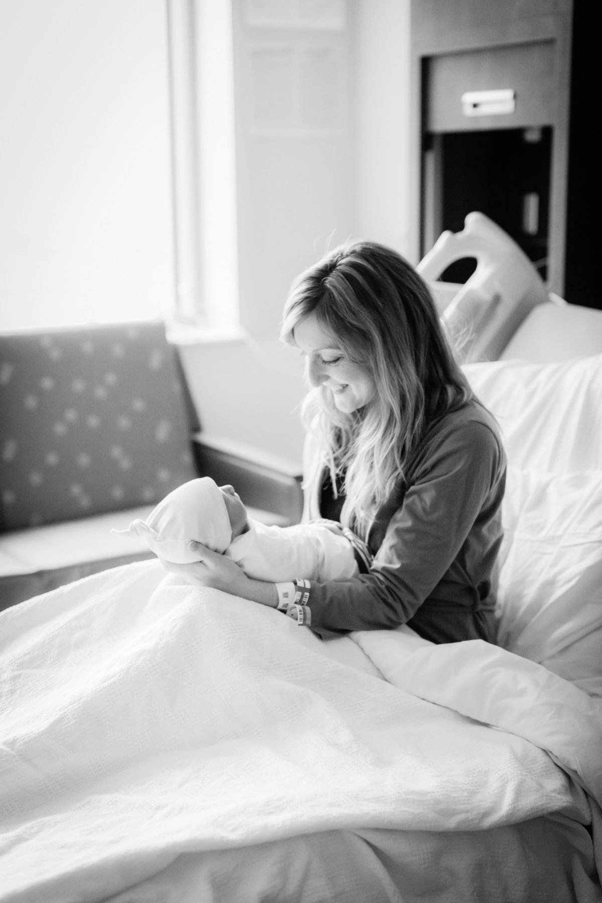mom holding baby in hospital bed for baby photos
