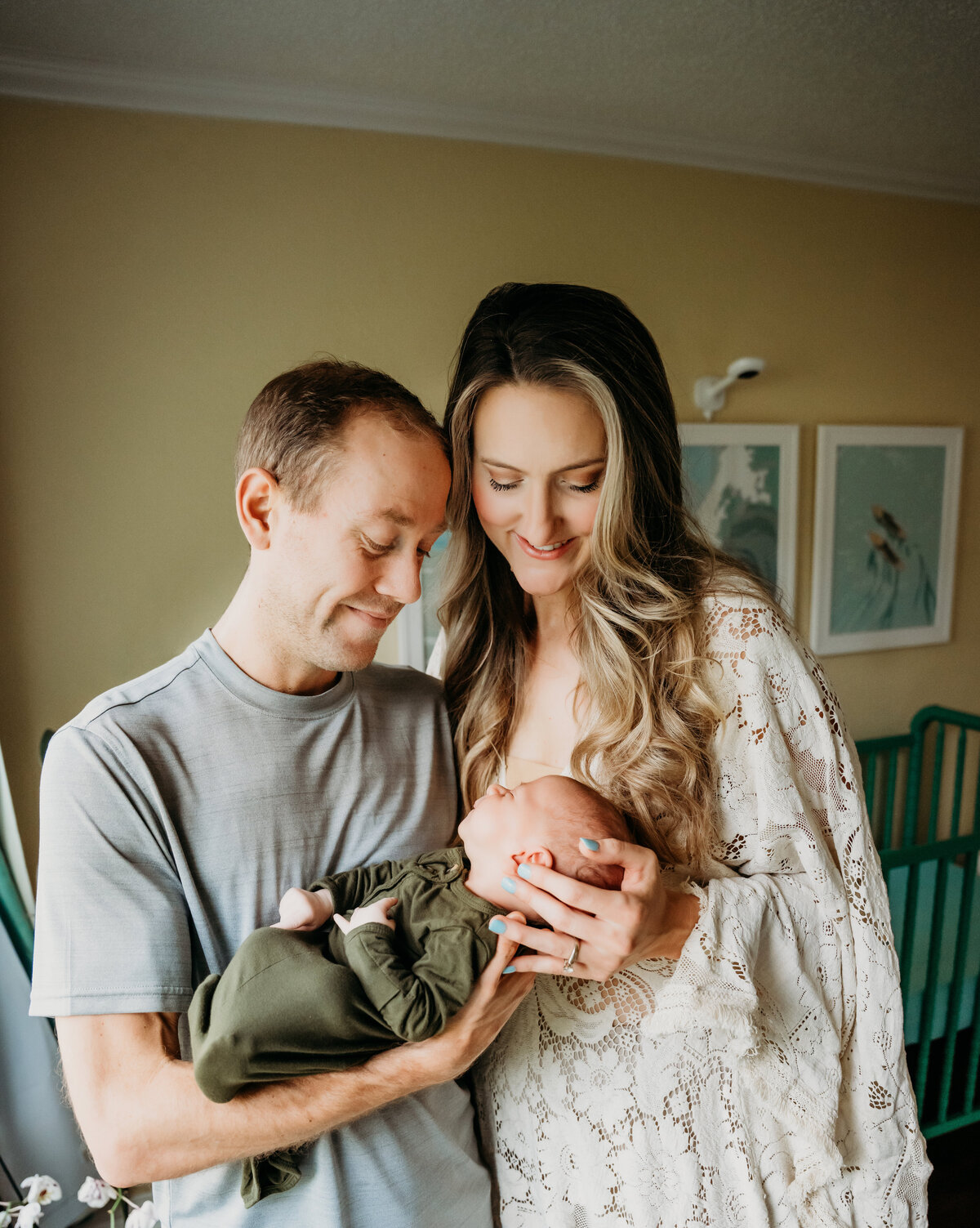 Newborn Photographer, a young mother and father stand together and admire their baby as dad holds him