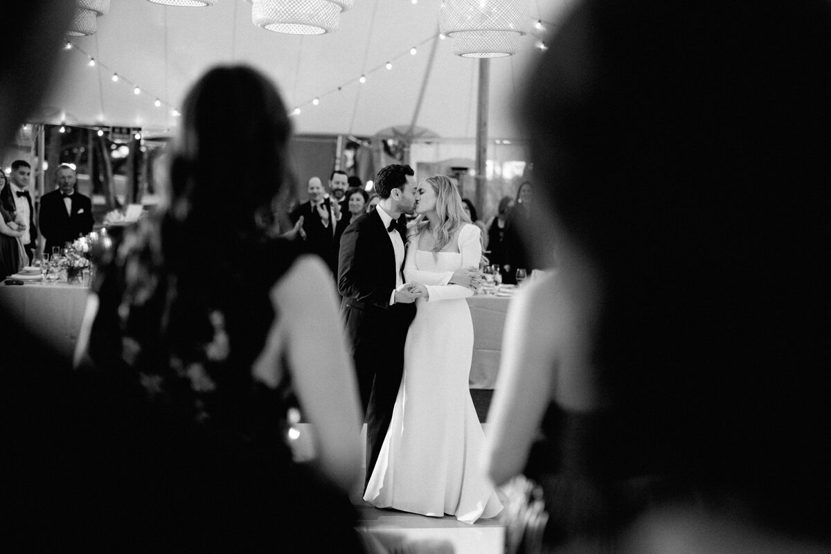 Bride and groom kissing during their first dance on a black-and-white checkered dance floor at their Longboat Key wedding by Florida wedding photographer Jake Ford.