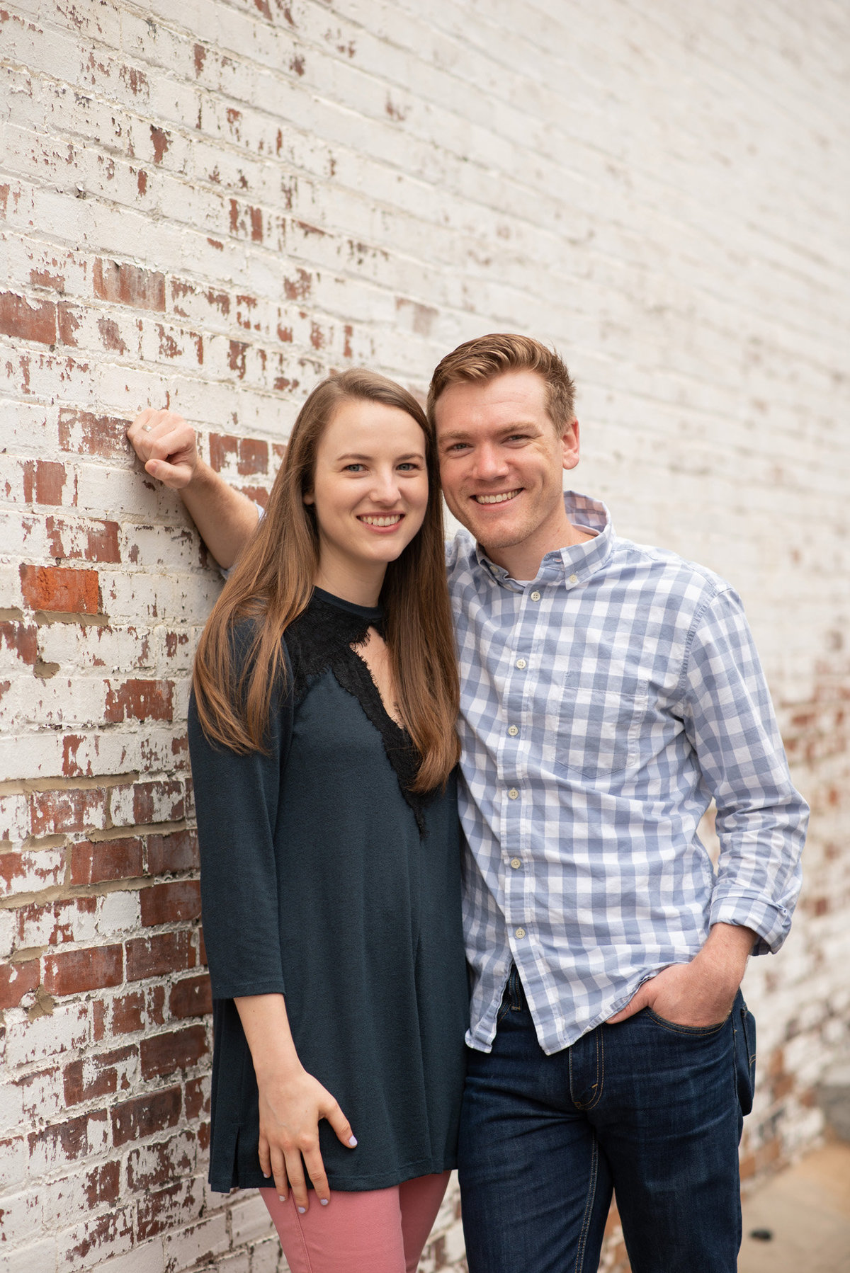 Young couple leaning against white-painted brick wall