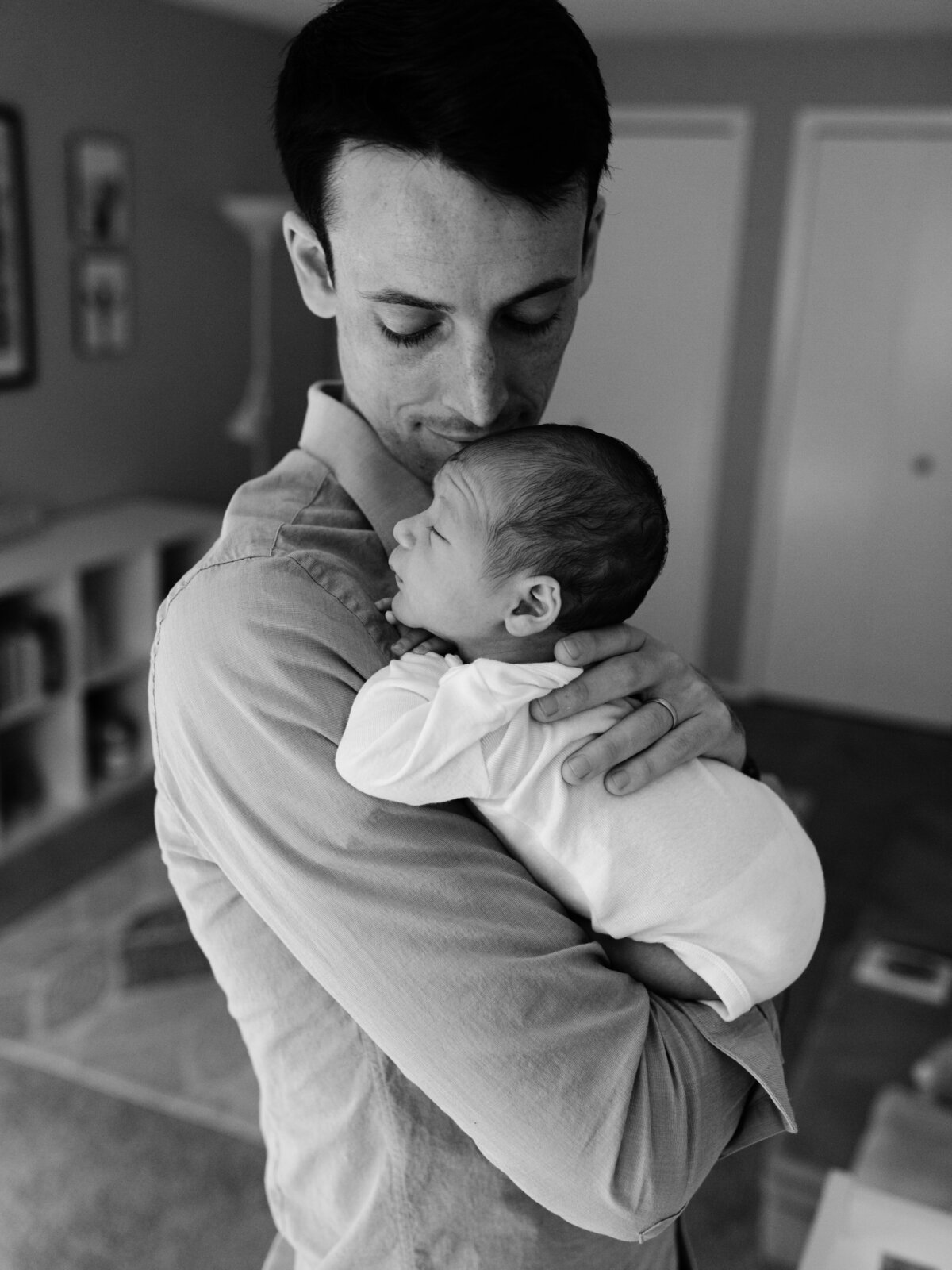 dad holding newborn baby boy in nursery