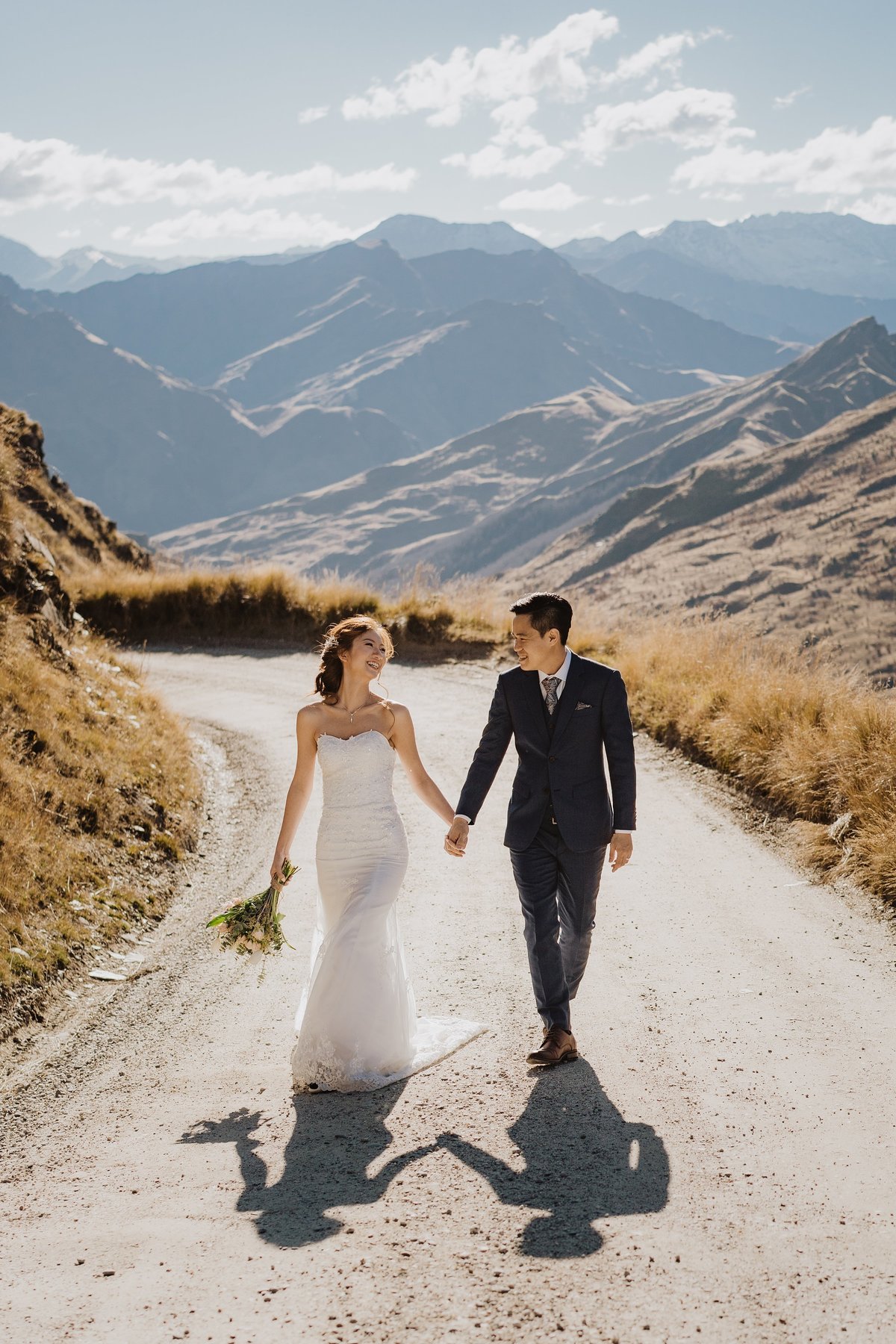 Bride and groom walking down a dirt road in the mountains