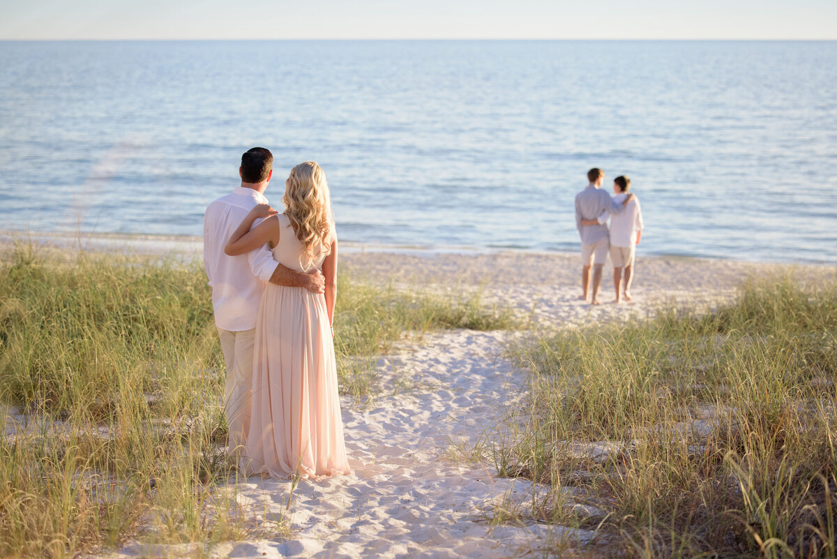 Parents standing back watching their two kids in the distance at the beach