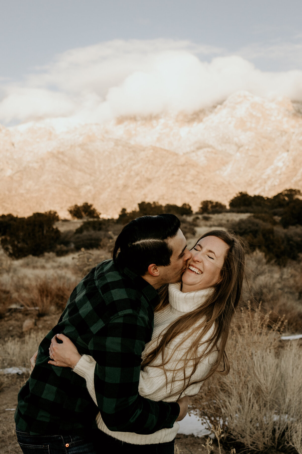 engaged couple hugging and laughing at the Sandia Foothills in New Mexico