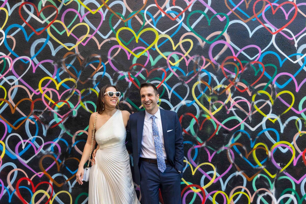 A couple leaning up against a colorful mural.