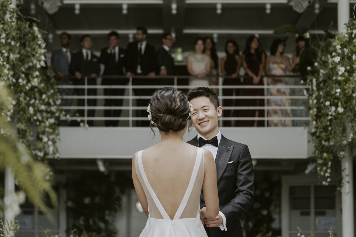 the groom smiling at his bride for the first look and witnessed by their friends