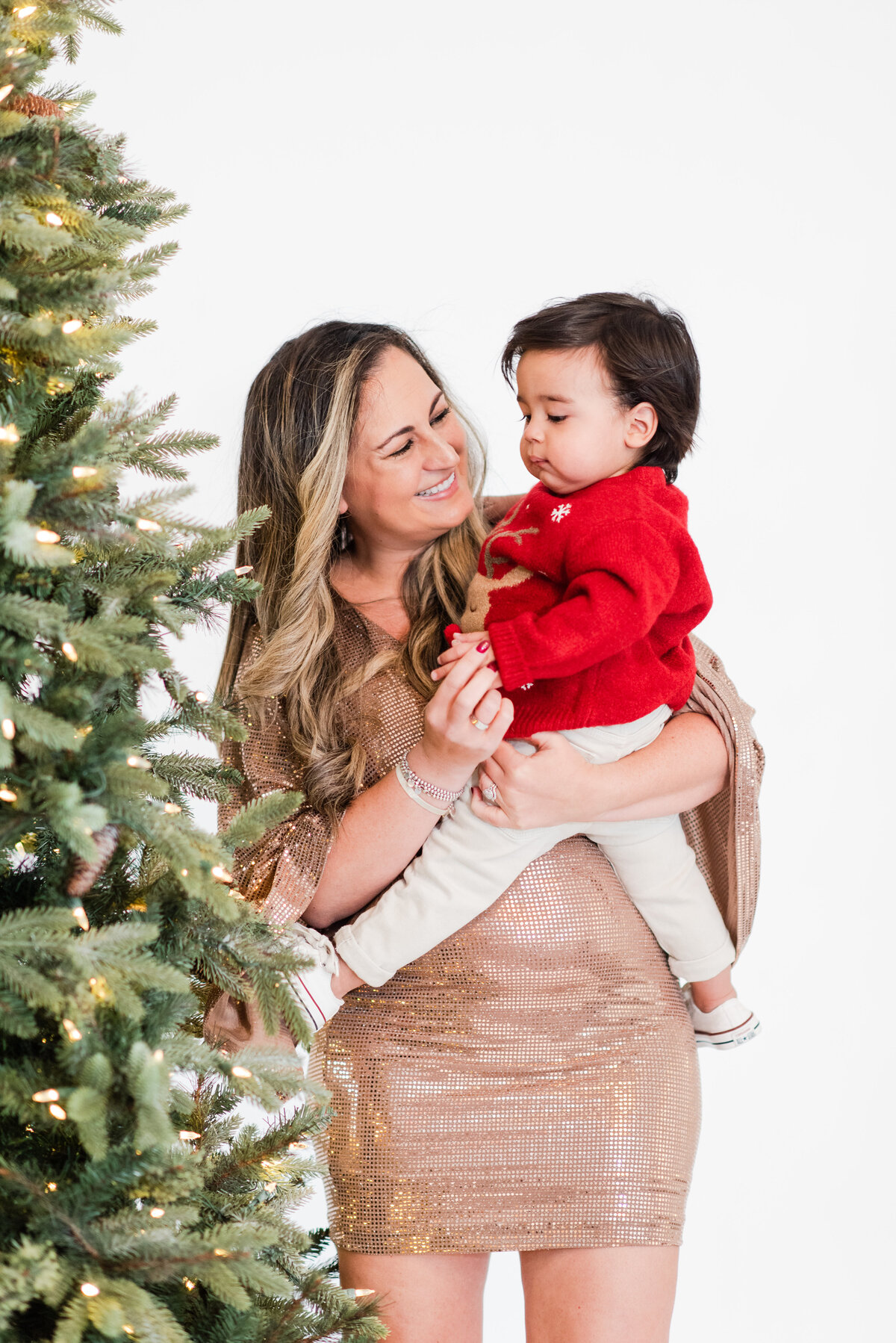 Mother and toddler son putting an ornament on a Christmas tree by Miami Christmas Mini Session Photographers