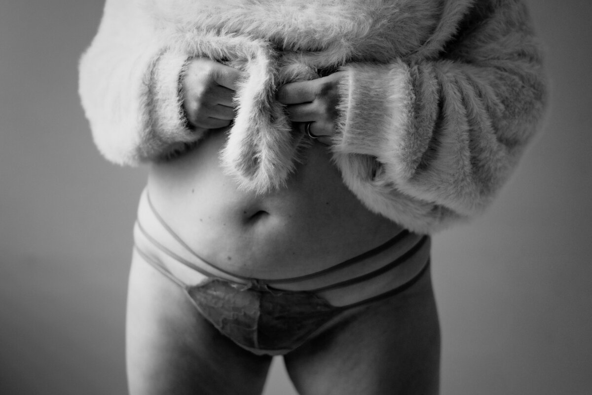 A person in their underwear lifting up their sweater.