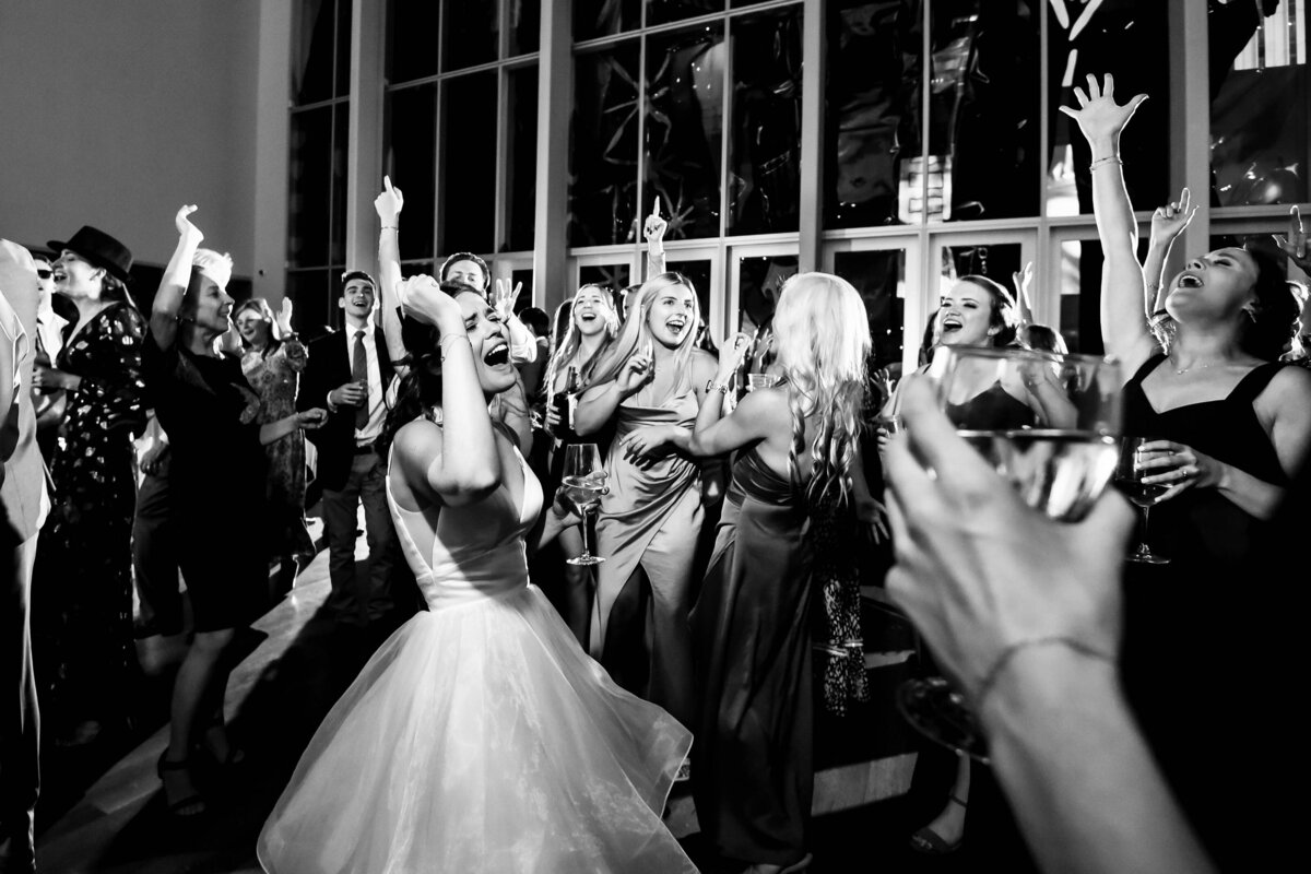 Black-and-white-candid-photograph-of-a-bride-and-her-guests-belting-out-song-lyrics-during-the-wedding-reception-at-The-Mint-Museum-Uptown