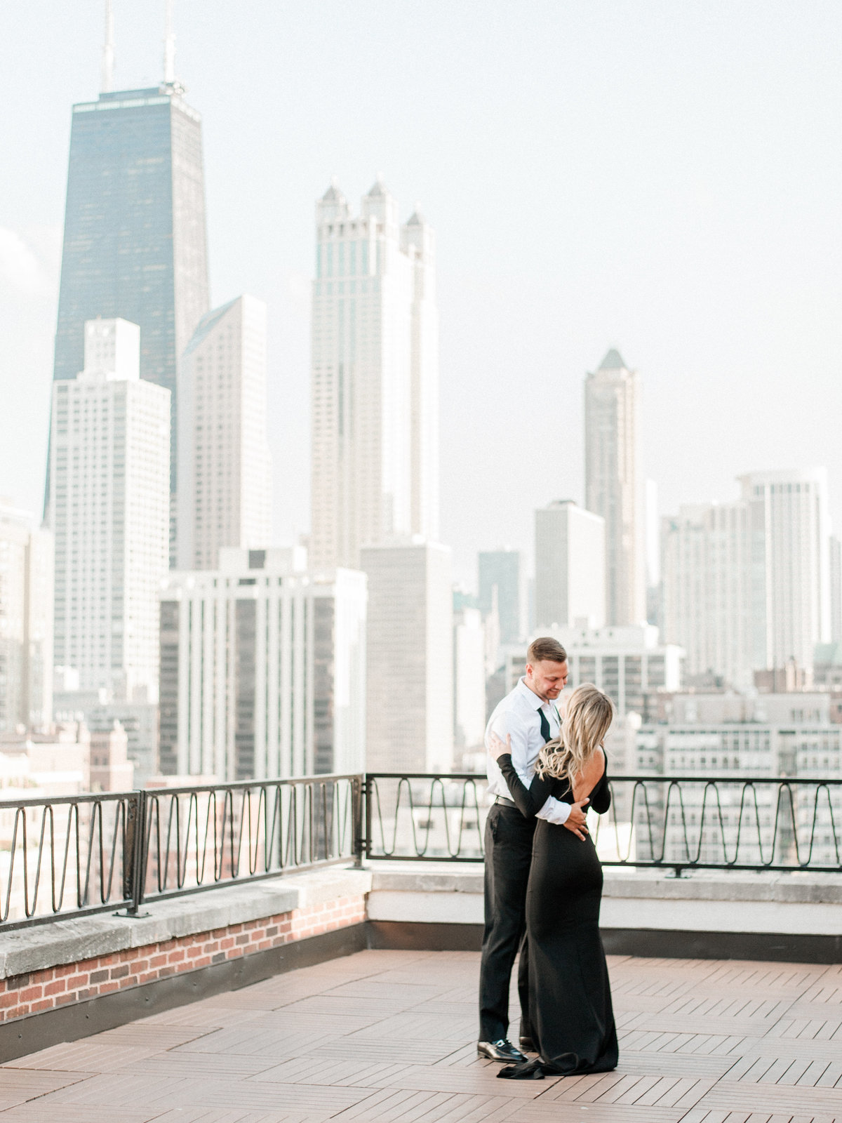 engaged couple dancing on rooftop with chicago skyline