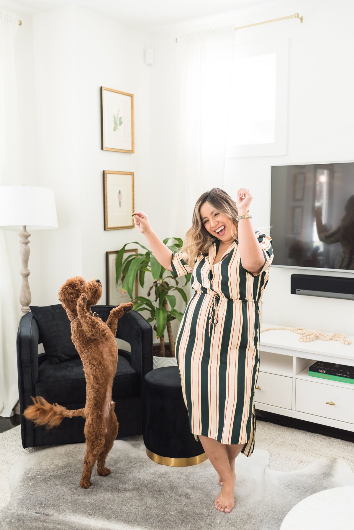 Latina business owner dancing with her dog in a living room for fun and casual personal brand photos