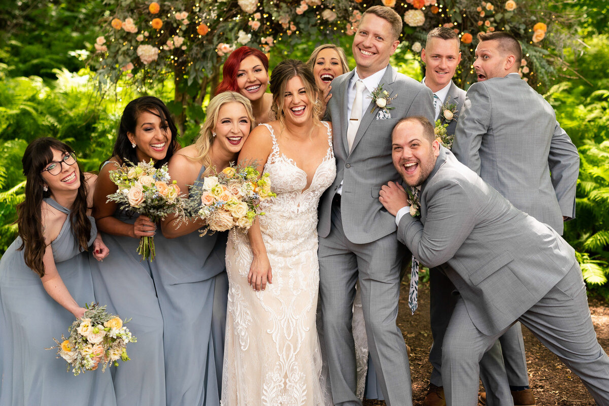 Bride and groom snuggle and laugh with wedding party in Stillwater, Minnesota.