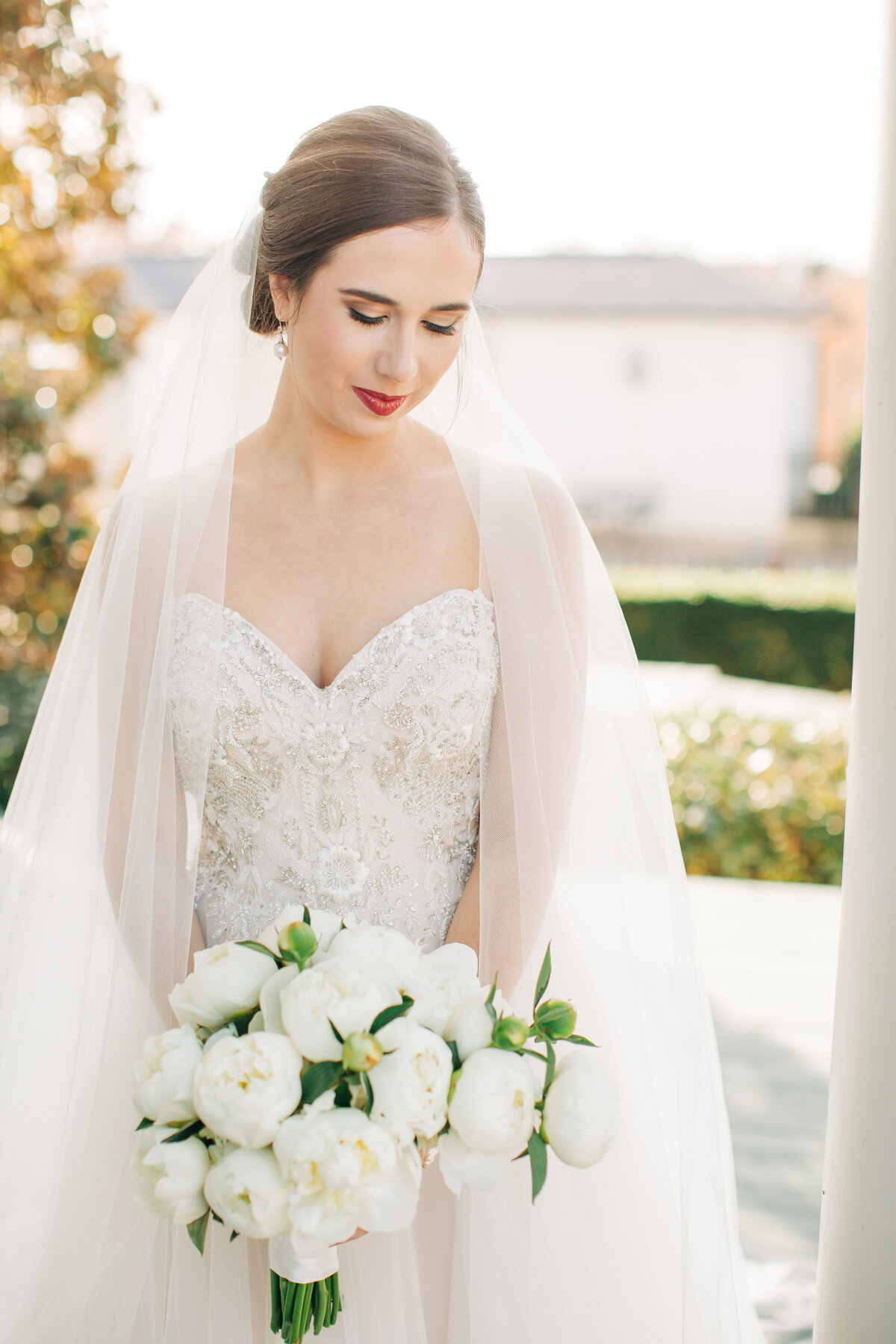 Wedding portrait of a bride in a sequined dress holding a bouquet of white peonies