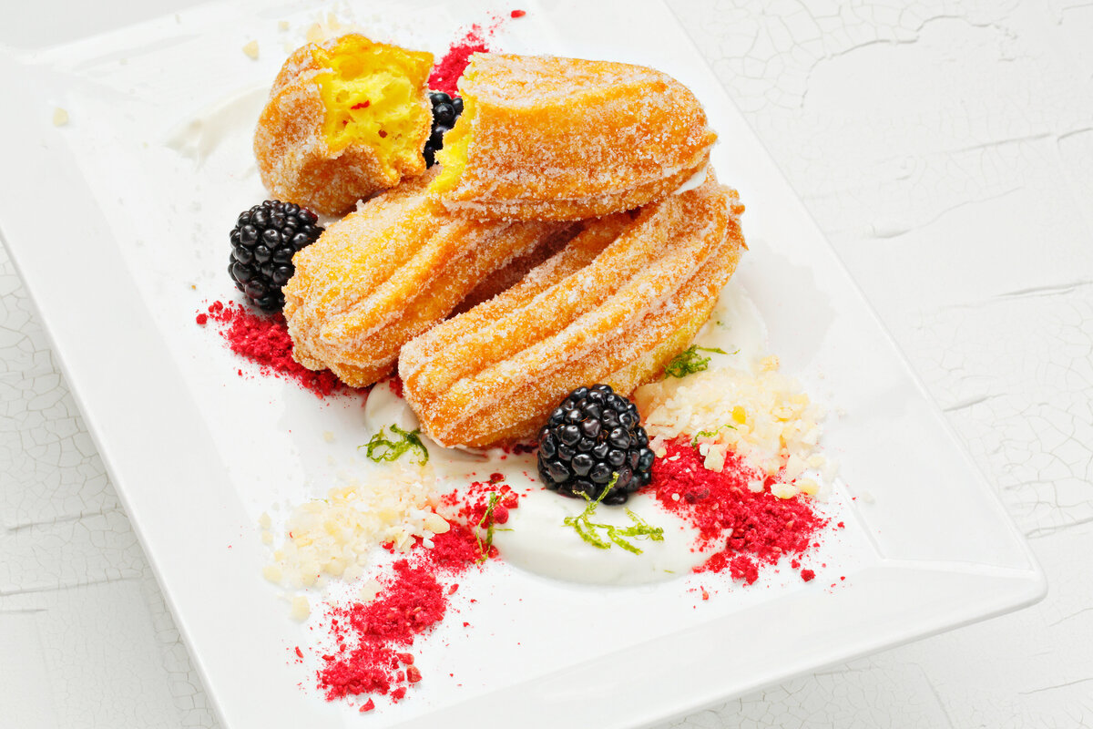 Filled churros on a plate with fruit