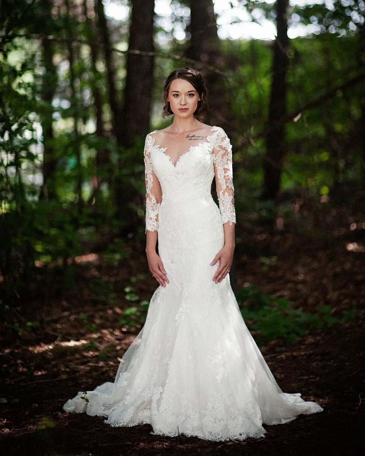 A bride standing in a wooded area.