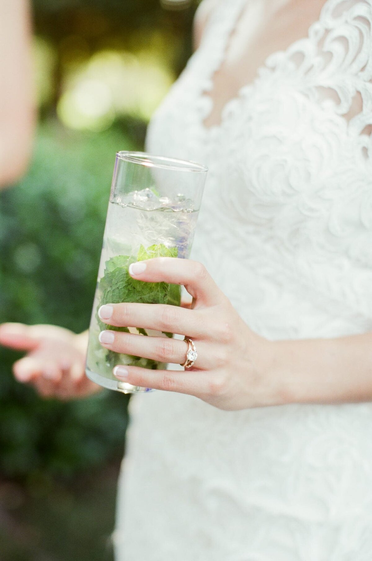 Wedding bride's hand holding a healthy drink with a wedding ring on her finger.