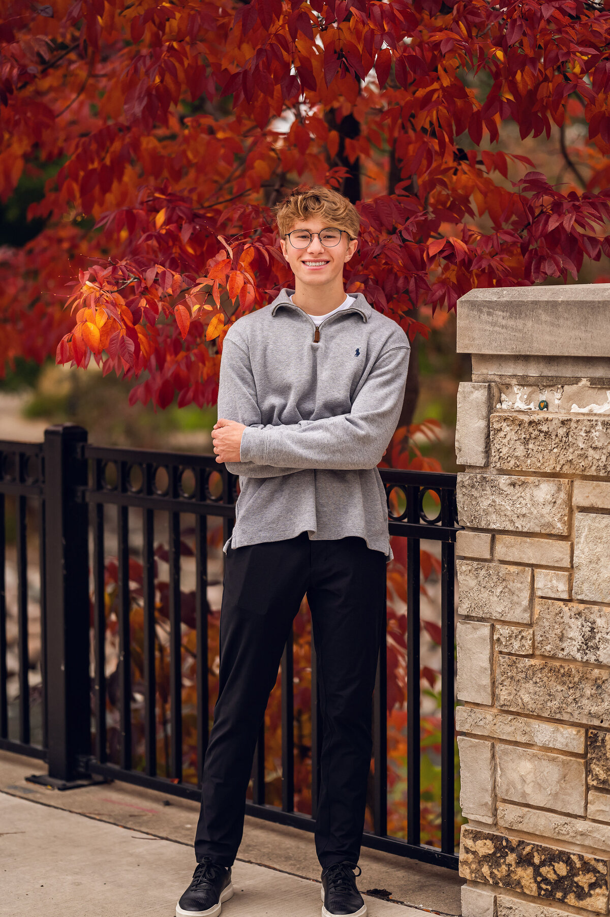 A senior student from Waukesha West High School stands in Frame Park surrounded by the red leaves of Fall.
