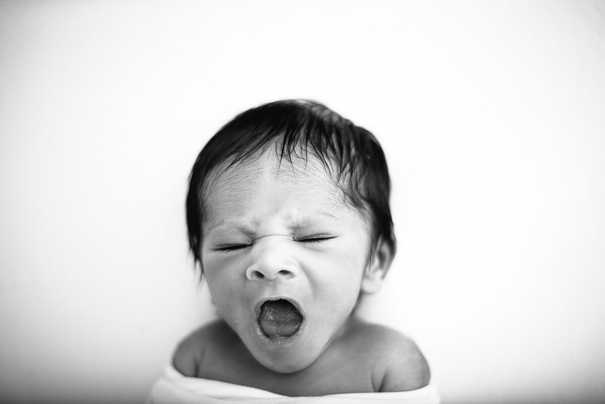 black and white newborn photo of baby yawning