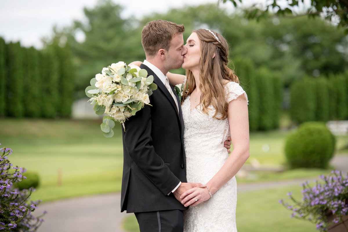 bride and groom kissing on the golf course at Willow Creek Golf and Country Club wedding photo