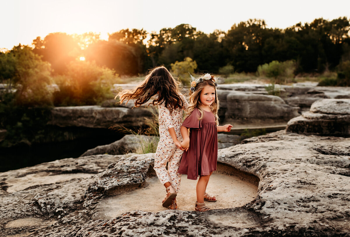Family Photography, Sisters twirling on the rocks at McKinney Falls.