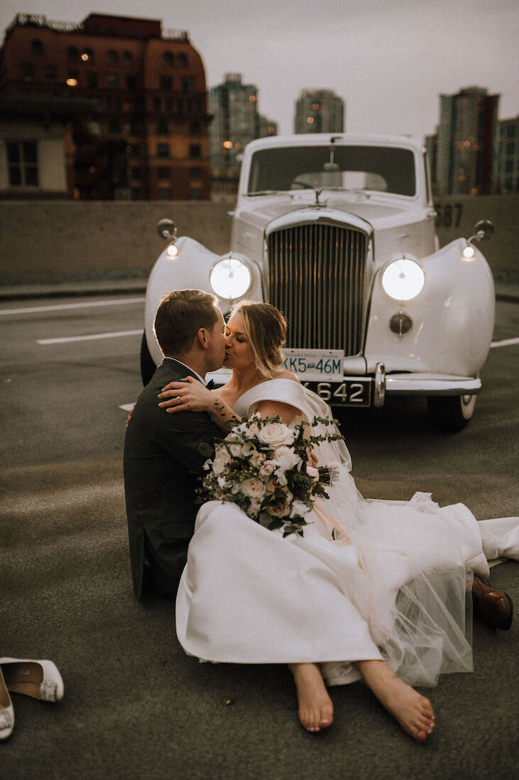 bride kissing groom beside car