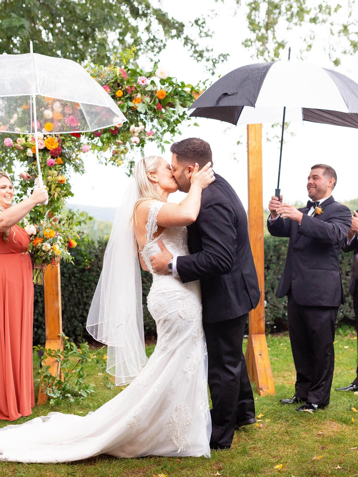 Bride and groom share a first kiss during their rainy ceremony.
