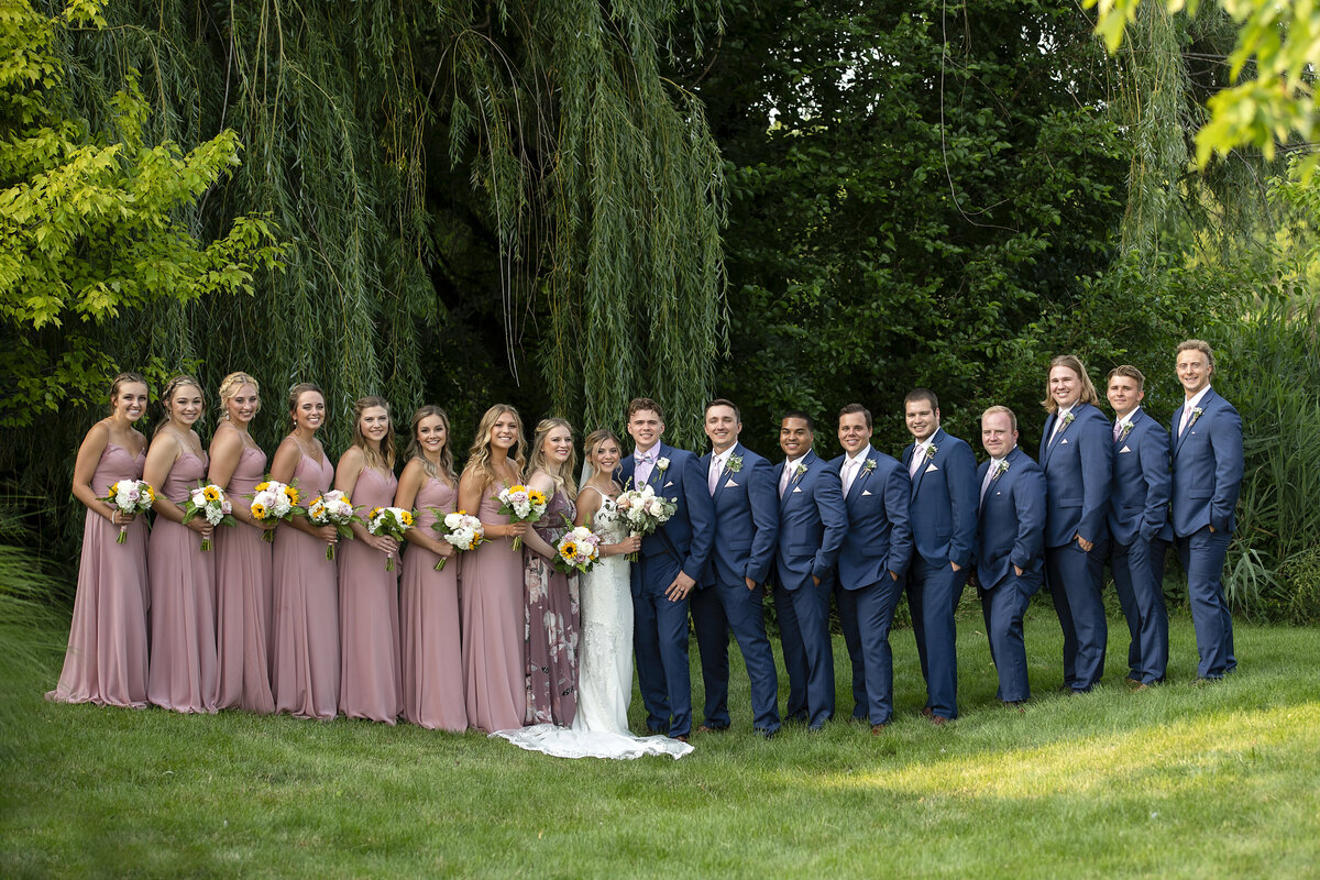Large bridal party posing  with bridesmaids on one side and groomsmen on the other sider and newlyweds in the middle