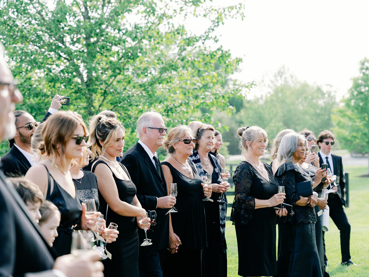 guests look towards the ceremony as they hold their champagne flutes
