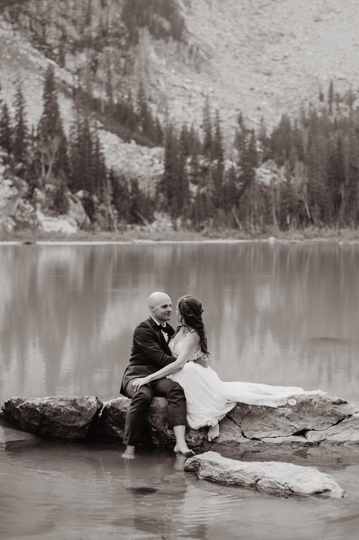 Jackson Hole Photographers capture couple hugging on rock during outdoor bridal portraits