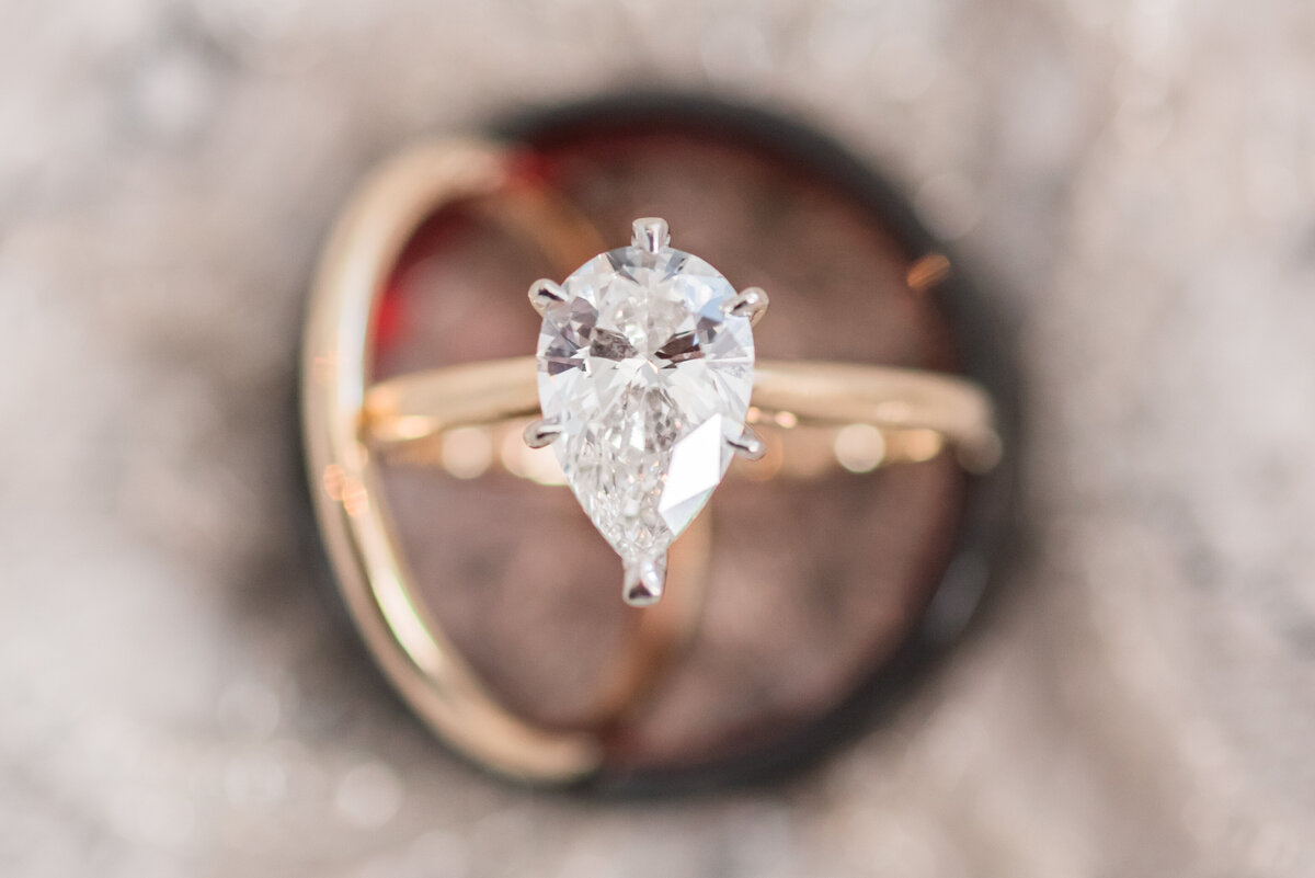 A close up image of an engagement ring resting on top of wedding bands