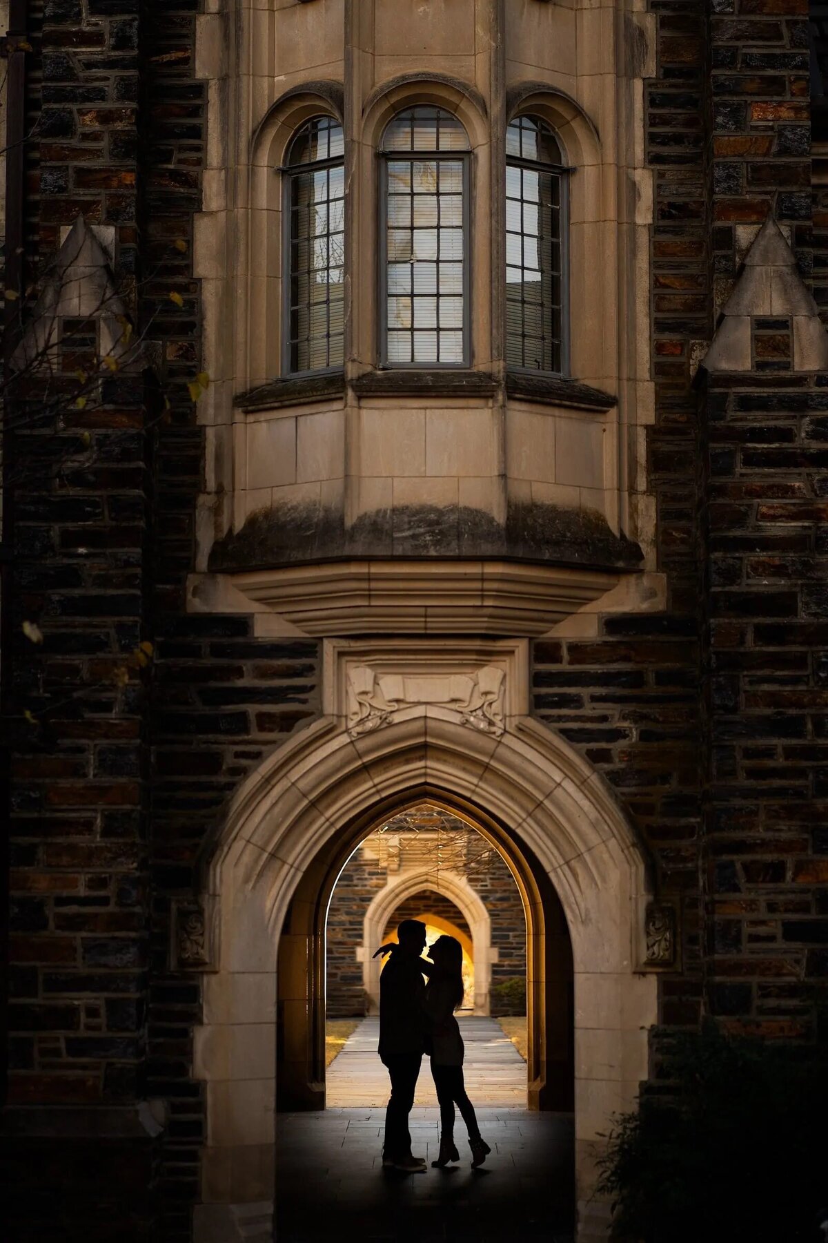 A couple stands in a dimly lit archway, their silhouetted figures set against the architectural beauty of the background
