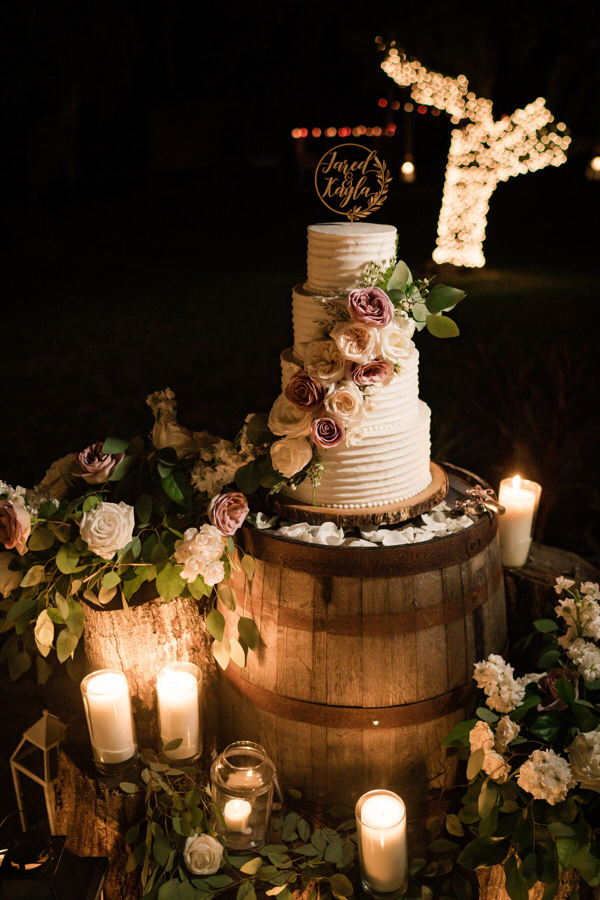 custom wedding cake on wood barrel with florals and candles at private residence