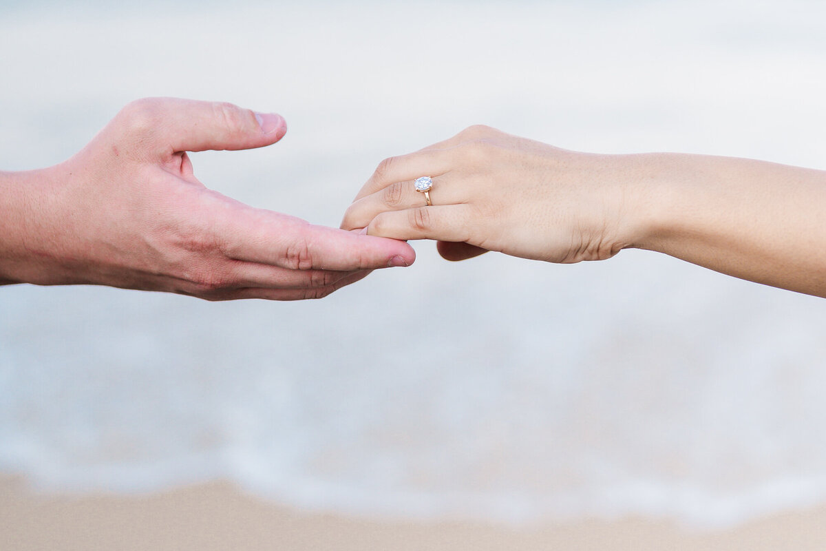 Two holding hands with an engagement ring on the beaches of Wilmington by a North Carolina wedding photographer, JoLynn Photography