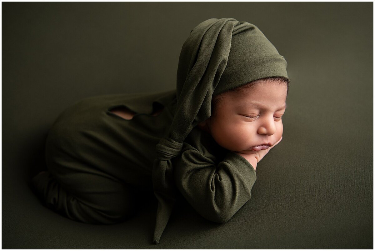 Sleeping newborn baby boy  dressed in a dark green outfit and sleepy hat