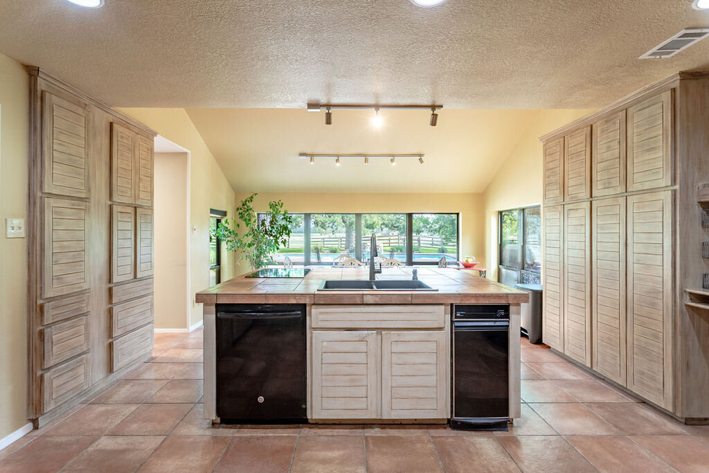 Large kitchen island with beautiful pool view in this 5-bedroom, 4-bathroom vacation rental house for 16+ guests with pool, free wifi, guesthouse and game room just 20 minutes away from downtown Waco, TX.