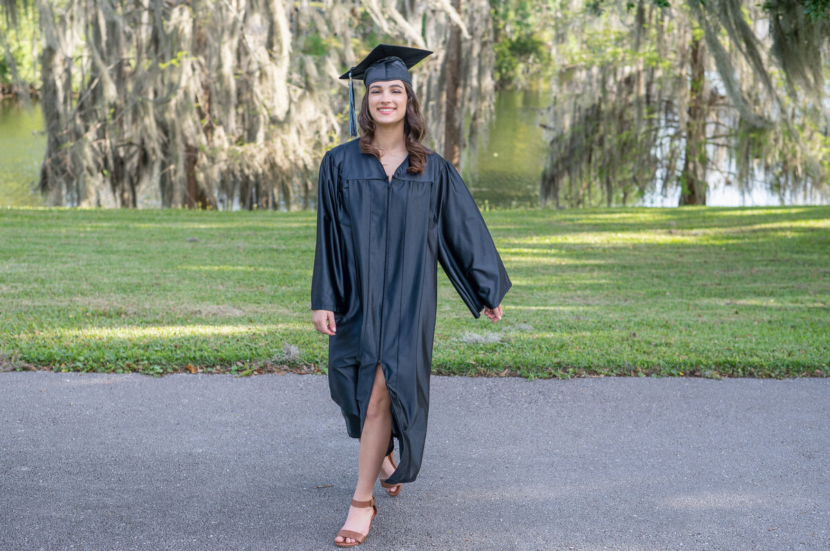 High school senior girl walking in cap and gown by Khim Higgins Photography.
