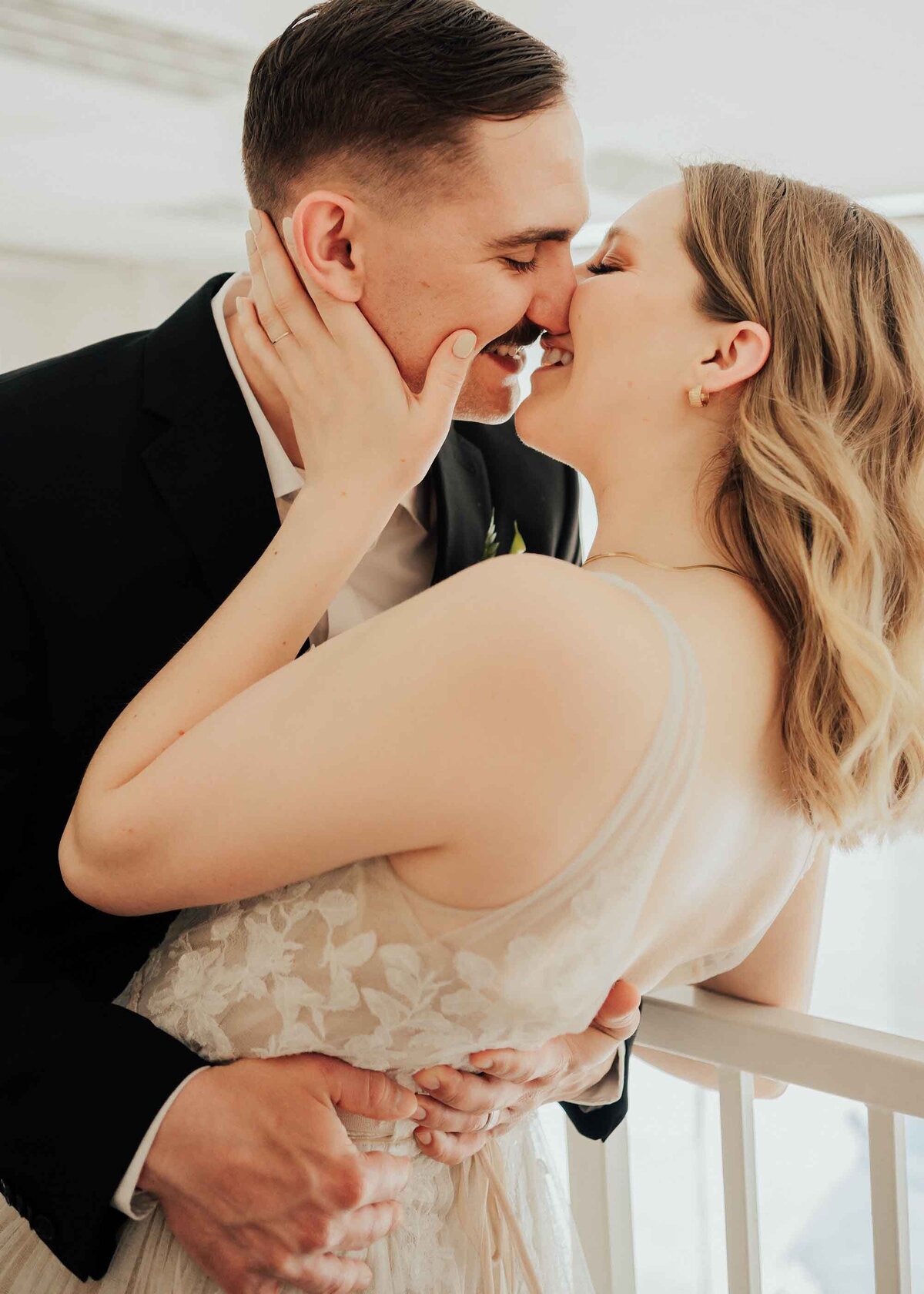 Maddie Rae Photography close up of bride and groom doing a slight dip kiss. her hand is on his face and his hands are on her waist