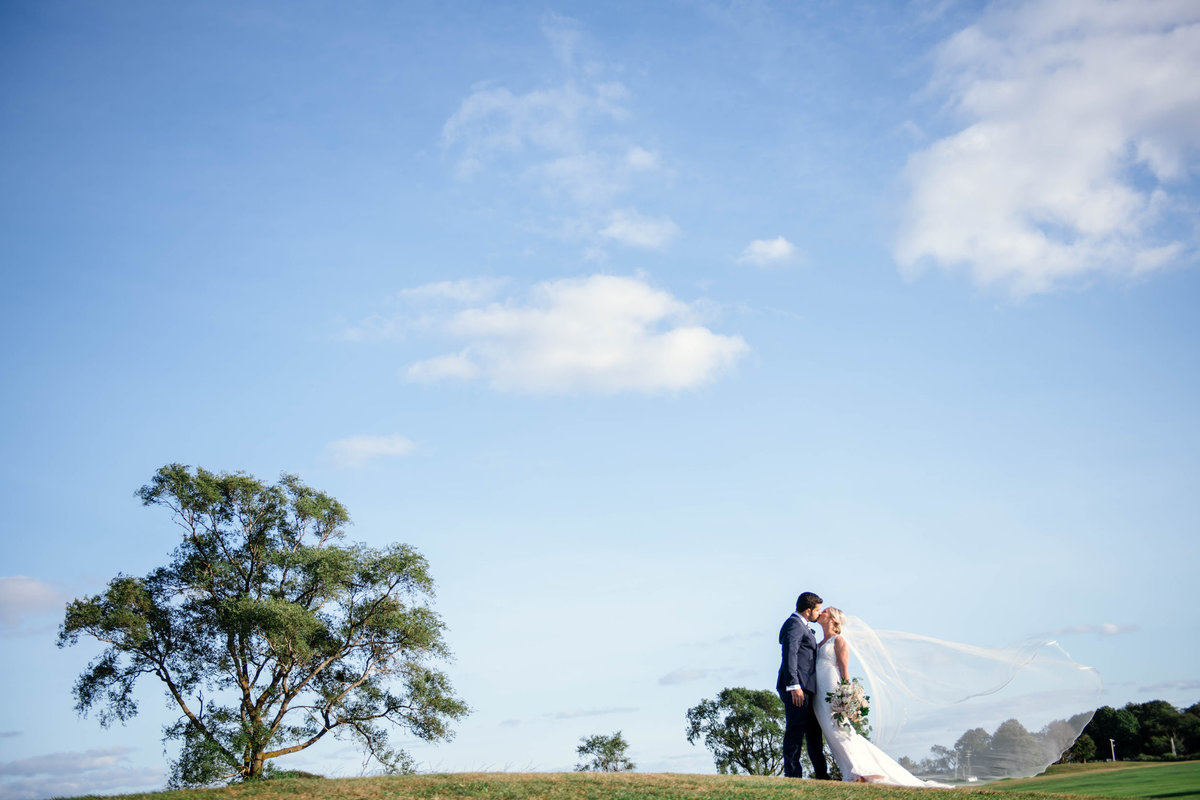 bride and groom kissing on the golf course for wedding at the Mansion at Timber Point