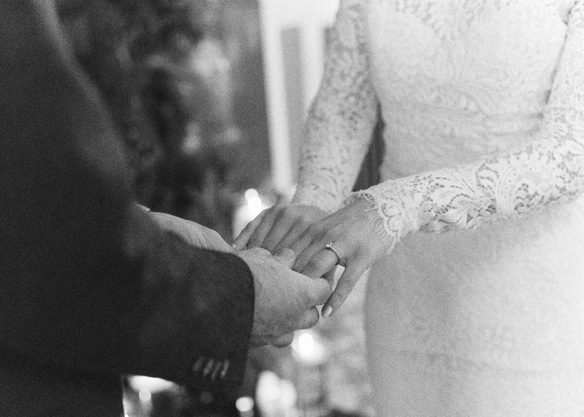 bride wearing lace wedding dress and groom holding brides arm during wedding ceremony captured on film camera