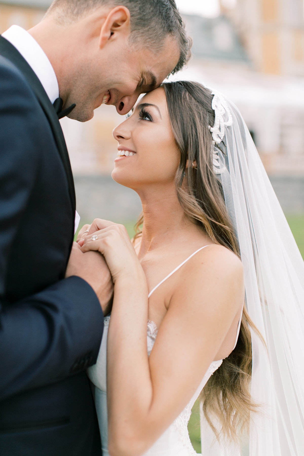 bride and groom touching foreheads and holding hands during bridal portraits