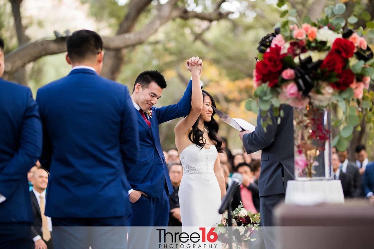 Newly married couple raise their arms as they are announced