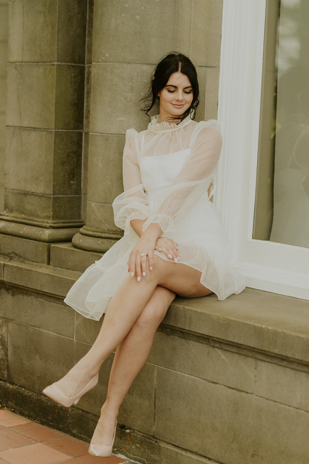 the-girl-sits-on-the-windowsill-an-a-white-dress-and-smiling