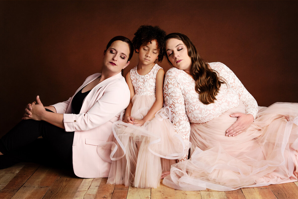 st-louis-maternity-photographer-expecting-mothers-posed-with-daughter-in-center-one-holding-pregnant-belly