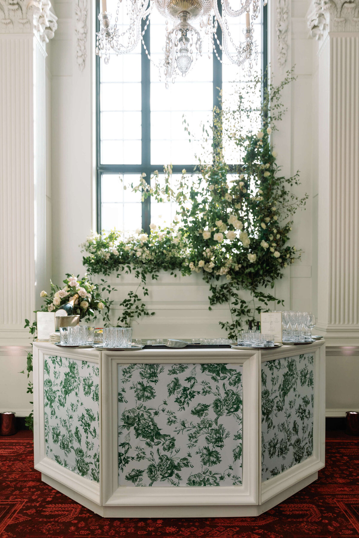 green and white floral pattern bespoke bar with real green and white flowers displayed behind it  on the window of the the ned hotel london for a luxury wedding